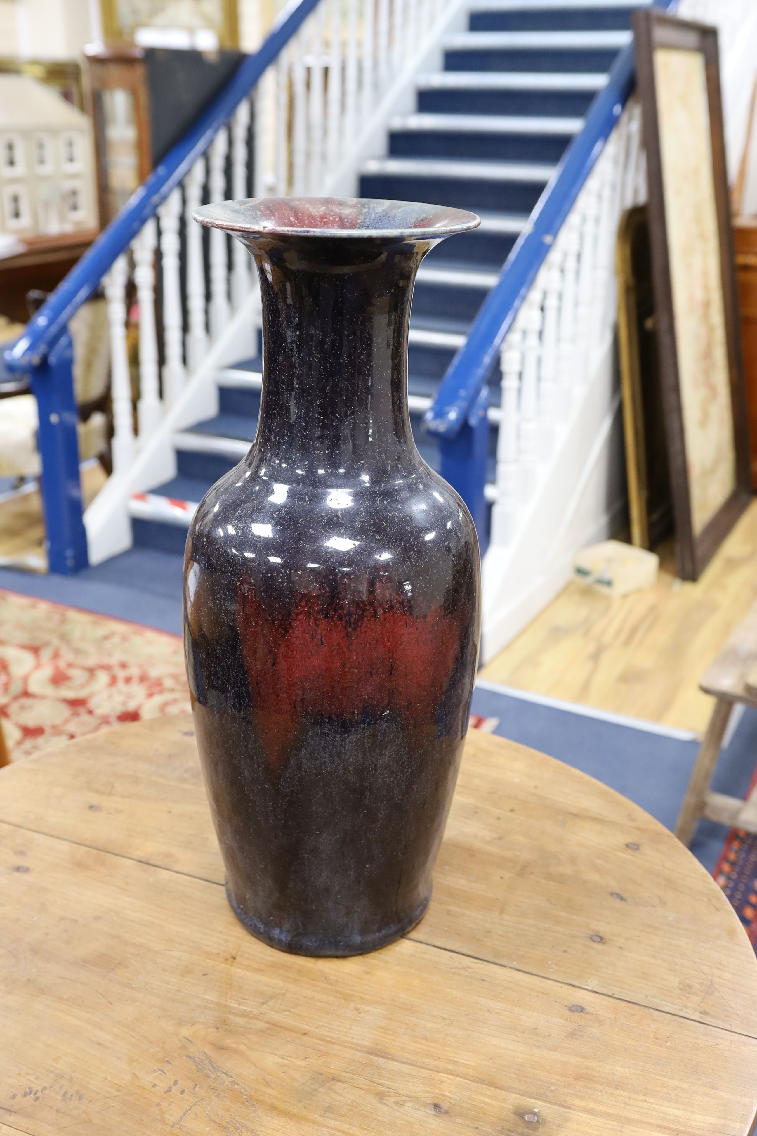 A large Chinese sang de boeuf glazed vase on carved wooden stand., Vase 61 cms high not including stand.